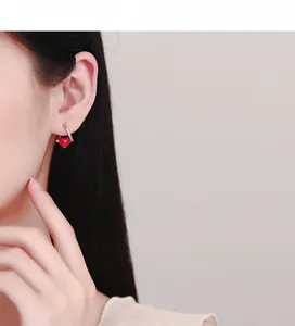 Close-up of a model wearing a red heart-shaped 925 silver hoop earring with polished finish
