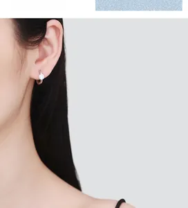 Gros plan d'une boucle d'oreille créole en argent 925 avec zircon sur une femme