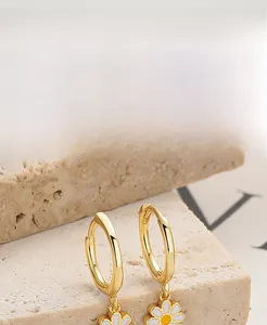 Close-up of S925 silver daisy earrings with white enamel petals on stone background