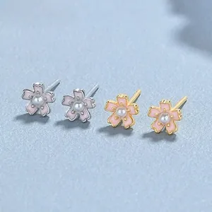 Detail von Blumen-Perlenohrringen in Silber- und Gold-Optik auf hellblauem Grund