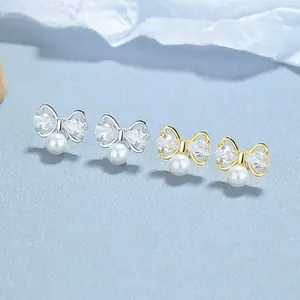Detailed view of 925 silver bow knot earrings with pearls and inlaid zircons in gold and silver