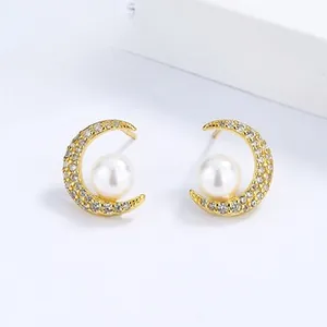 Macro shot of 925 silver gold moon earrings with white pearls and sparkling cubic zirconia