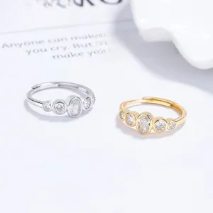 Detail view of silver and gold adjustable rings featuring five bezel-set cubic zirconia stones