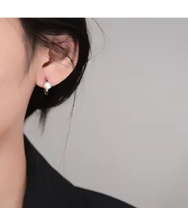 Detailed view of silver hoop earring featuring a rainbow opal stone on a female model