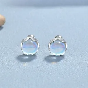 Macro shot of S925 silver crown earrings with iridescent moonstone gems on blue surface