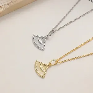 Vue macro de colliers en éventail or et argent avec texture ondulée et bords perlés précis