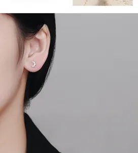 Gros plan de boucles d'oreilles croissant en argent S925 portées sur le lobe d'oreille