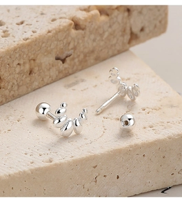 Détail macro de boucles d'oreilles croissant en argent 925 sur fond en pierre travertin