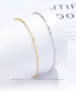 Close-up of gold and silver square link chain bracelets on white display stand