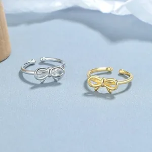 Detail view of adjustable gold and silver bow rings with polished metal finish