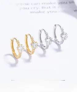 Detail of gold and silver star earrings with cubic zirconia on a minimalist ear hoop
