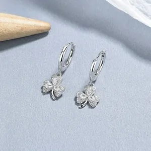 Macro detail of 925 sterling silver hoop earrings with pavé zircon clover charms