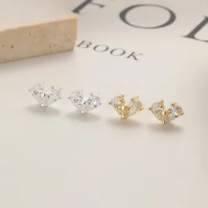 Macro shot of silver and gold zircon heart stud earrings with prong setting