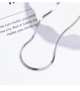 Macro shot of 925 sterling silver flat herringbone chain on white decorative plate