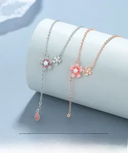 Detail view of silver and rose gold cherry blossom necklaces with pearls and enamel petals
