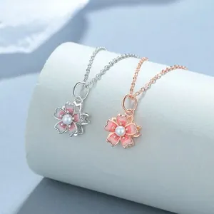 Macro detail of cherry blossom necklaces with pink enamel petals and pearl center