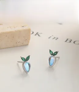 Detail of 925 sterling silver carrot stud earrings with moonstone and green gems