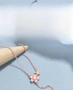 Detail of rose gold S925 silver cherry blossom pendant with a white pearl on a wood stand