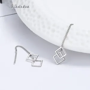 Macro shot of 925 sterling silver long chain earrings with hollow geometric square pendants