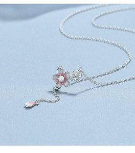 Macro shot of pink enamel cherry blossom necklace with white pearl and silver chain