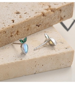 Macro shot of S925 sterling silver carrot earrings with moonstone and green gemstones
