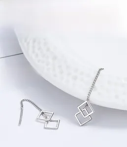 Macro shot of S925 sterling silver geometric hollow square tassel earrings on white porcelain