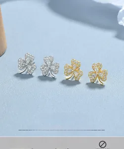 Macro detail of silver and gold clover stud earrings with sparkling pavé cubic zirconia