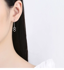 Detail shot of long sterling silver ear threader with hollow geometric square pendants