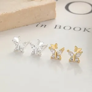 Details von silbernen und goldenen Schleifenohrringen mit Zirkonia auf einer Steinoberfläche