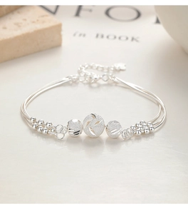 Macro detail of multi-strand silver bracelet with three matte engraved transfer beads