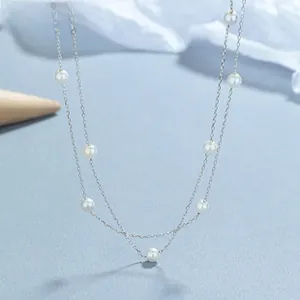 Detail of 925 sterling silver chain necklace with elegant white round pearls on blue background