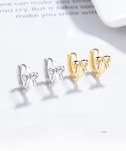 Detailed view of silver and gold bow hoop earrings on a stylish lifestyle background