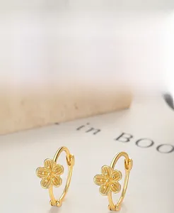 Détail de boucles d'oreilles fleur en argent sterling 925 plaqué or sur livre