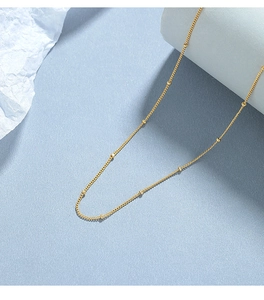 Detailed close-up of a minimalist 925 silver beaded chain necklace in gold finish