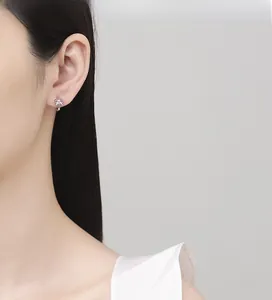 Macro detail of high-polished 925 sterling silver bow earrings worn by a model
