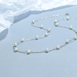 Double-layered 925 sterling silver necklace with round white pearls on a blue background