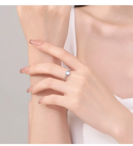Close-up of a minimalist 925 silver ring with a glowing round moonstone on a finger