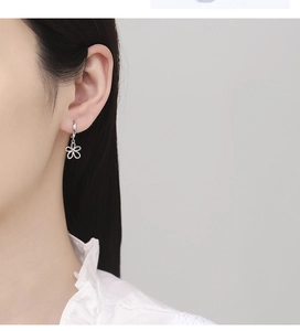 Close-up of a 925 sterling silver hollow flower charm earring on a female model