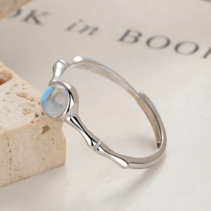 S925 sterling silver bamboo open ring with a round iridescent moonstone on stone book background