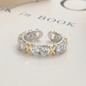 Detailed close-up of 925 sterling silver open ring with white zircons and gold X design