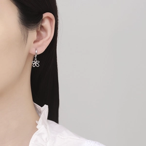 Minimalist 925 sterling silver hollow flower hoop earrings worn on a model's ear