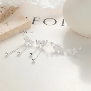 Macro detail of silver flower earrings with delicate chain tassels on white background