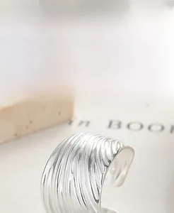 Macro shot of 925 sterling silver ring with wide wave textured design and open band