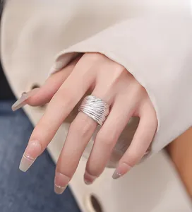 Detail of wide 925 sterling silver ring featuring a vertical wavy texture on model's hand