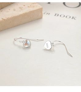 Détail des boucles d'oreilles en argent et pierre de lune avec poinçon S925 sur fond de pierre