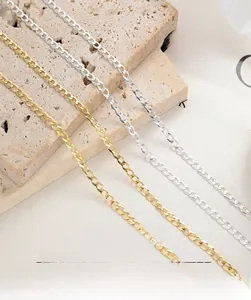 Detailed view of interconnected silver and gold curb chains on a textured stone surface