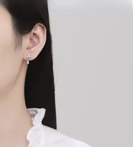 Detail of silver leaf stud earrings with zircon drops worn on a female model