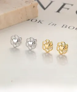 Detail of silver and gold hollow flower stud earrings with heart center on stone plate