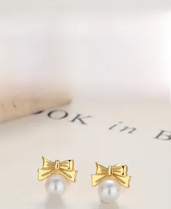 Detail of S925 sterling silver bow earrings with round white pearls in gold finish