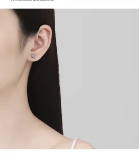 Close-up of elegant S925 sterling silver hollow flower stud earrings worn by a model